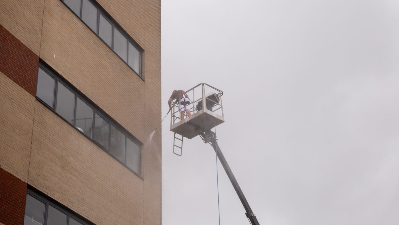 Worker on a cherry picker cleaning the facade at Pulse